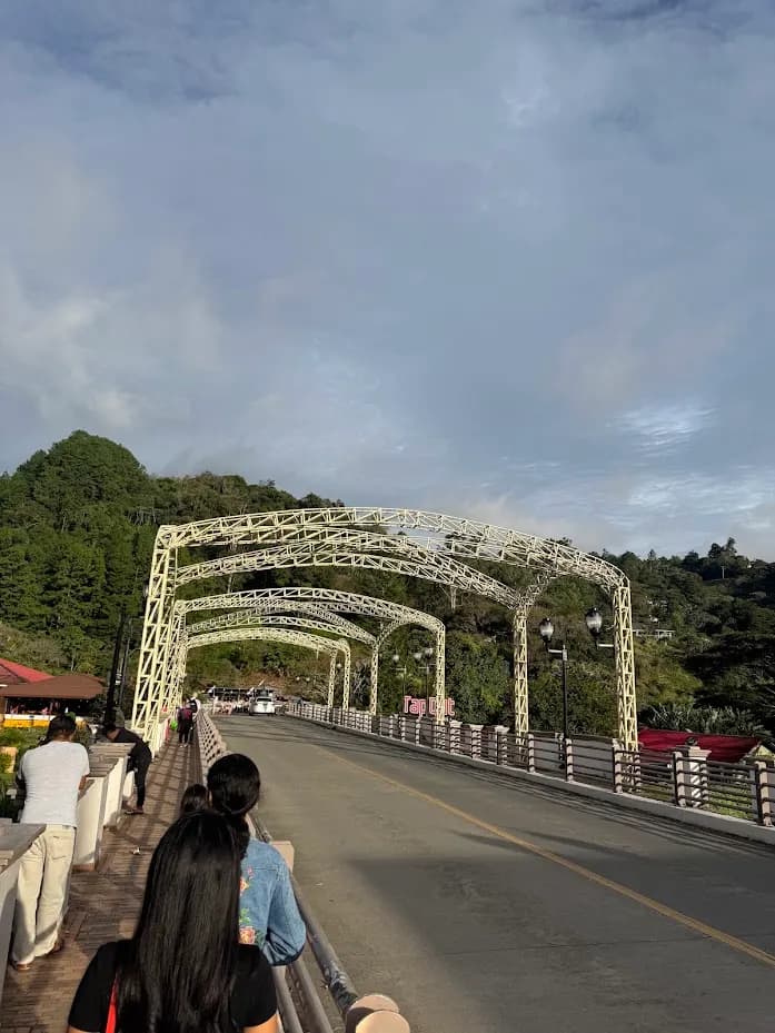 Walking across the steel arch bridge over the Río Caldera in Boquete, with green hills behind
