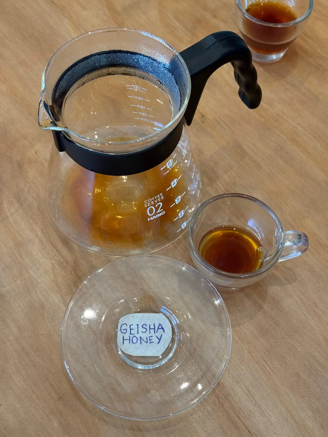 A coffee tasting flight with a glass carafe and cup of Geisha coffee