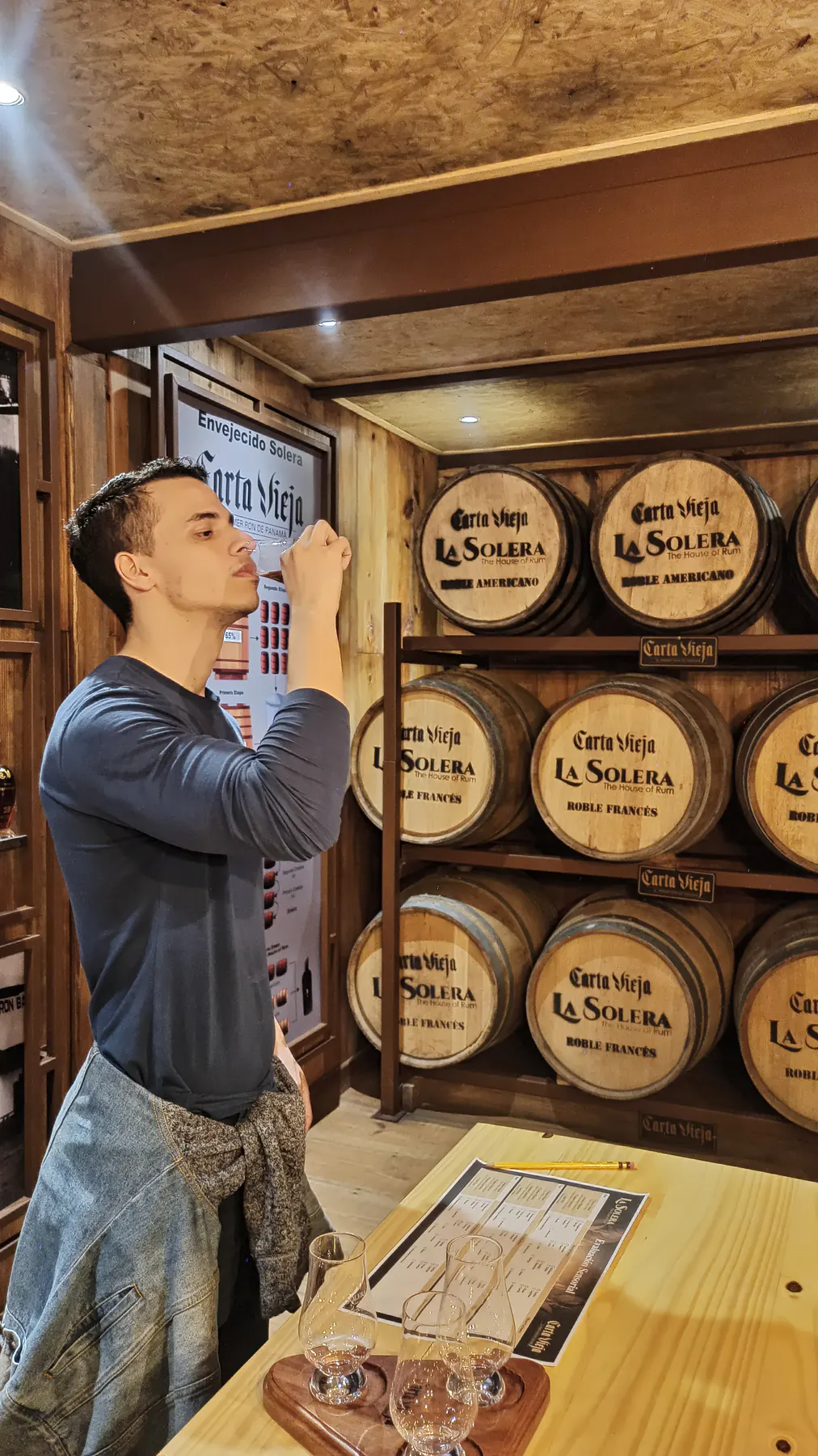 A guest smelling a glass of aged rum next to stacked barrels