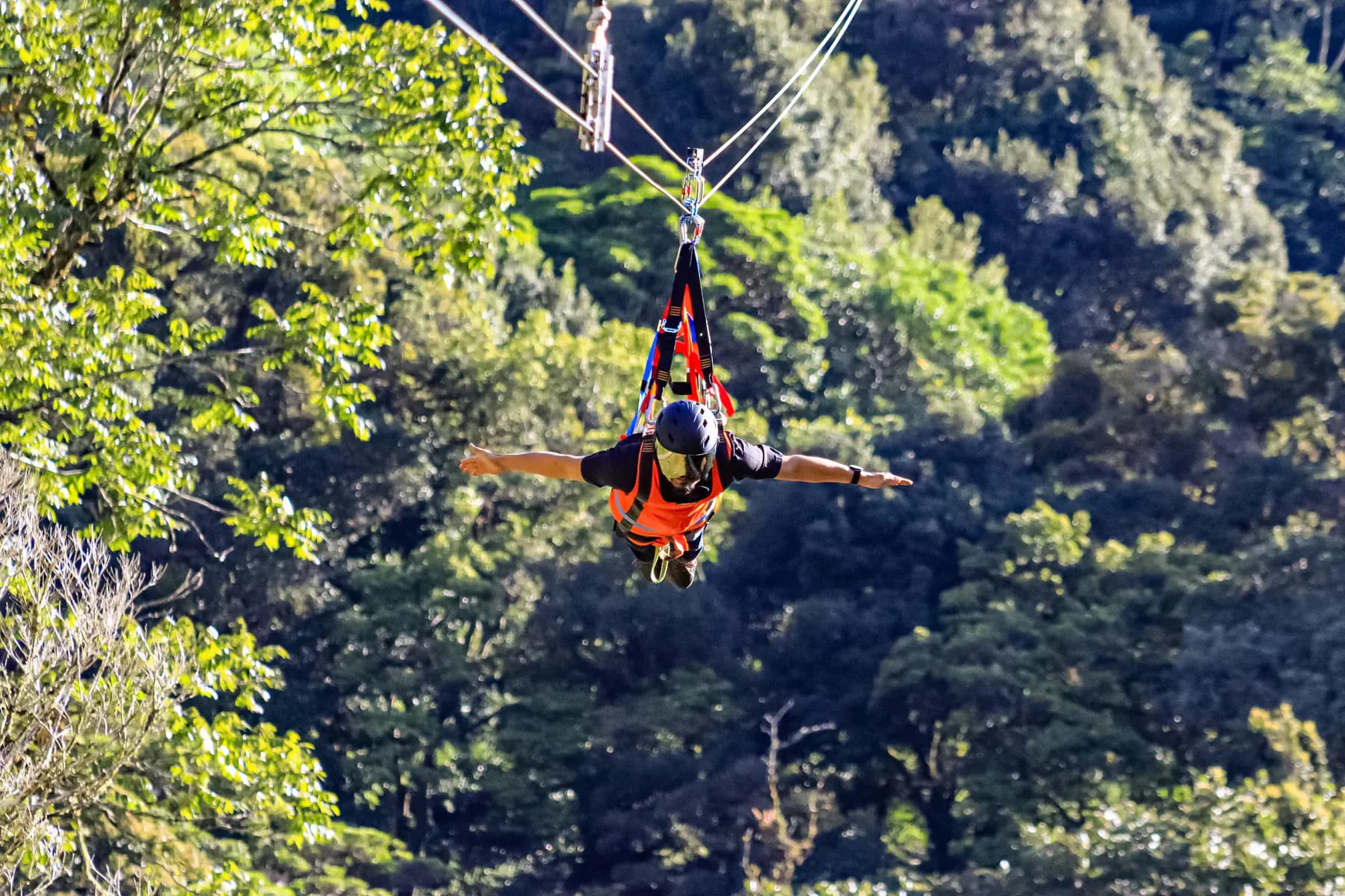 A rider crossing a forested valley on the long Superman zipline near Boquete