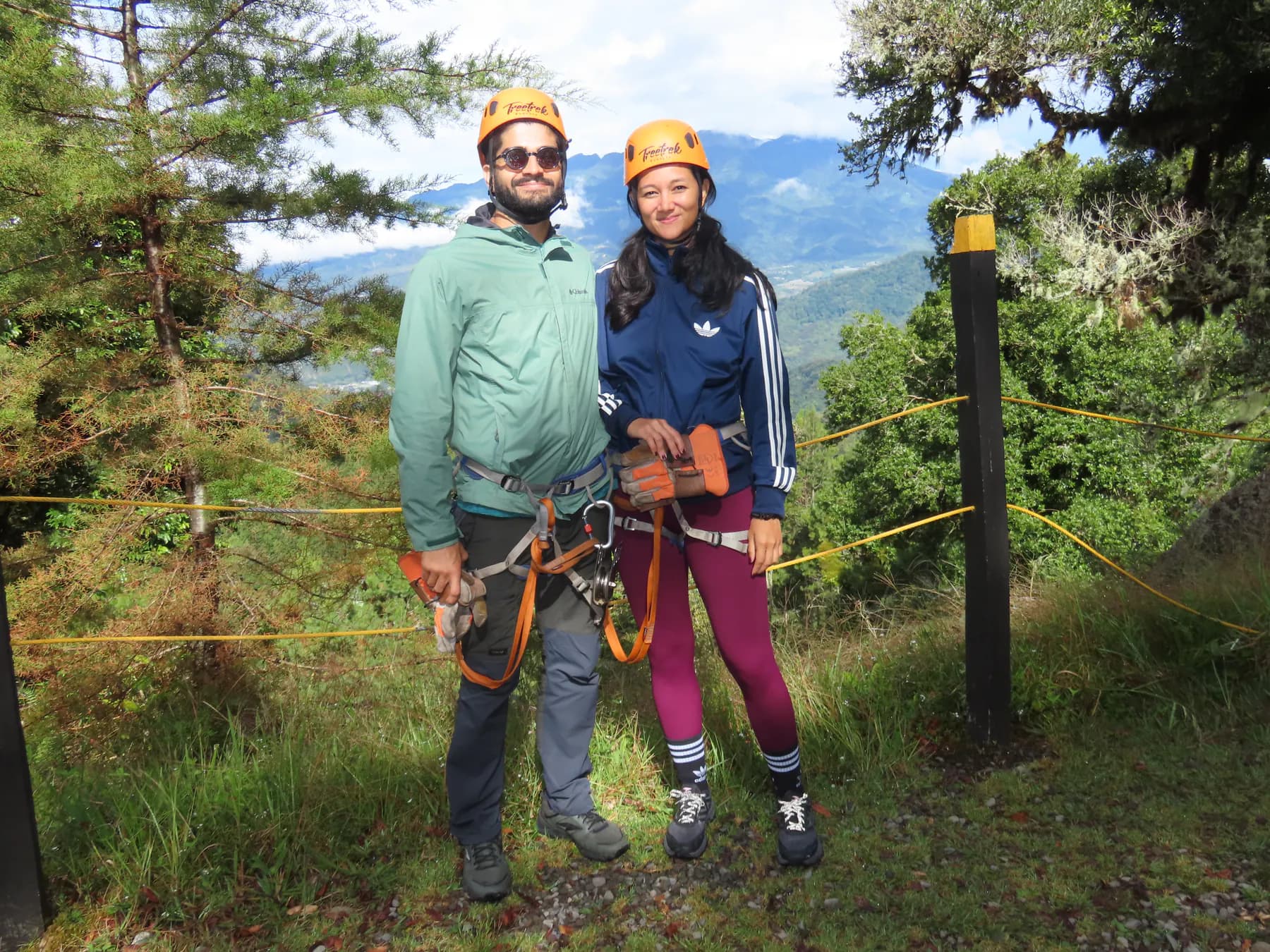 A couple in zipline harnesses and helmets with the Chiriquí mountains behind them