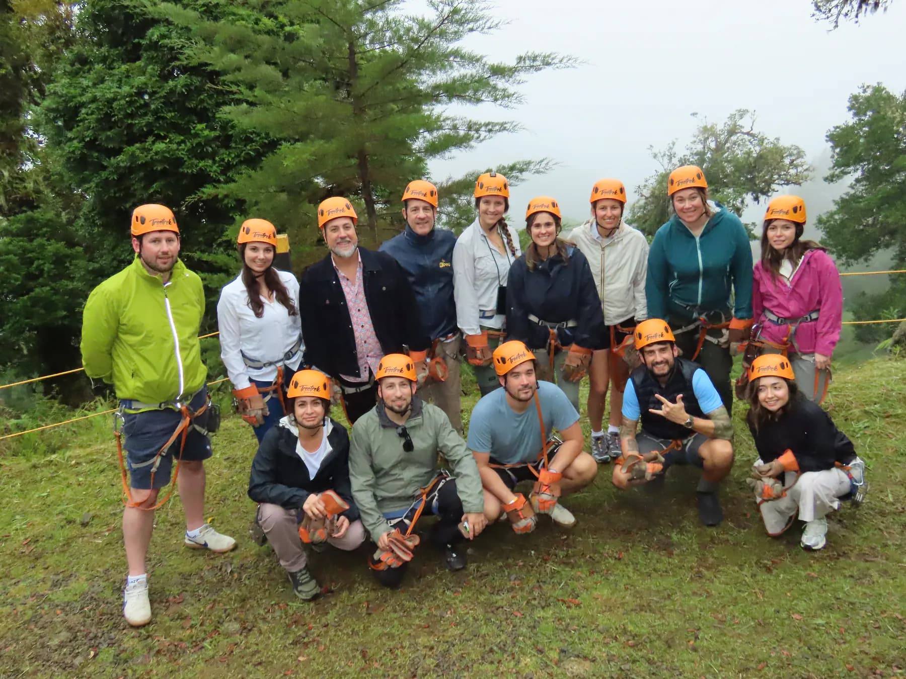 A group posing in harnesses and helmets on the grass after ziplining in Boquete