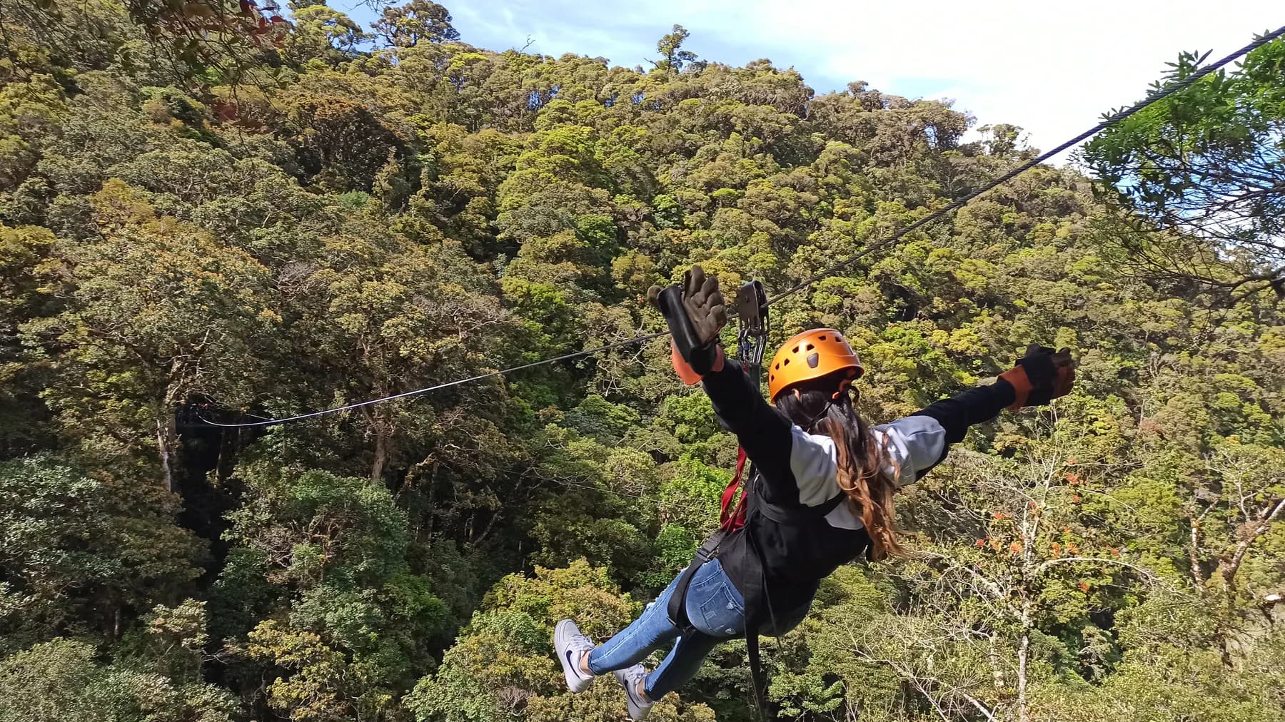 A zipline rider with arms spread wide flying over the cloud forest near Boquete